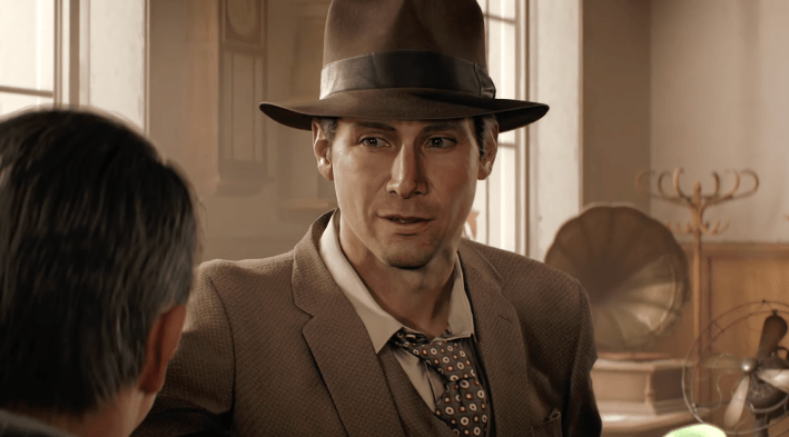 A screenshot from video game Indiana Jones and the Great Circle: Indiana Jones in a brown hat, brown suit coat, white shirt, and brown tie with white spots, standing in an office