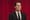 Agent Dale Cooper (Kyle MacLachlan) a man in a black suit, stares off into the middle distance in front of a red curtain.